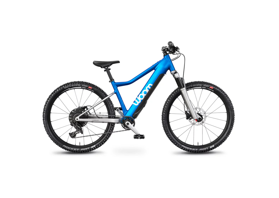 Blaues Mountainbike mit „woom“-Logo auf dem Rahmen, mit breiten schwarzen Reifen, Vorderradfederung und einem schlanken Design, vor weißem Hintergrund.