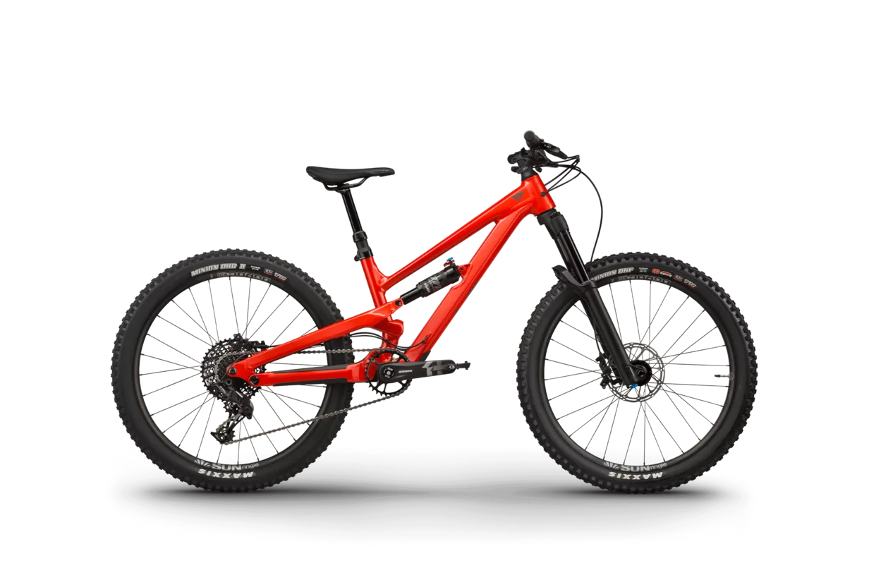 Leuchtend rotes Mountainbike mit dicken, profilierten schwarzen Reifen auf hellgrauem Hintergrund. Das Fahrrad verfügt über einen robusten Rahmen und ein modernes Design, das einen abenteuerlichen und dynamischen Eindruck vermittelt.
