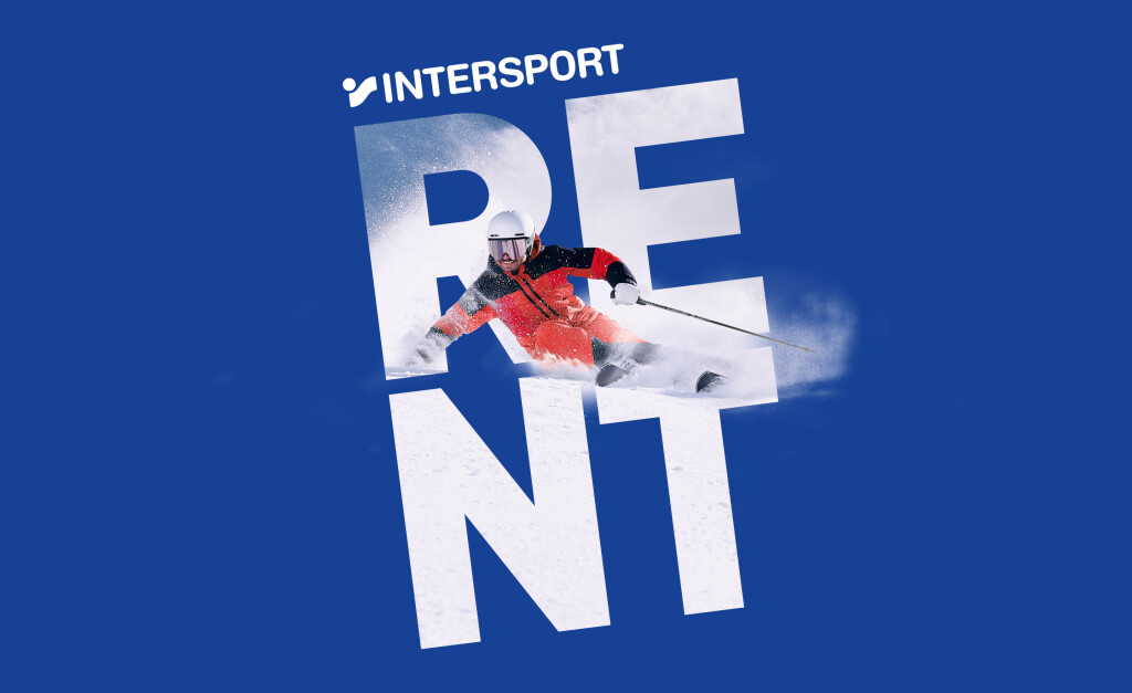 Ein Skifahrer in rot-schwarzer Kleidung gleitet durch den Schnee und schneidet dabei durch auffällige weiße Buchstaben, die auf blauem Hintergrund das Wort „RENT“ bilden. Die Szene vermittelt Geschwindigkeit und Spannung.